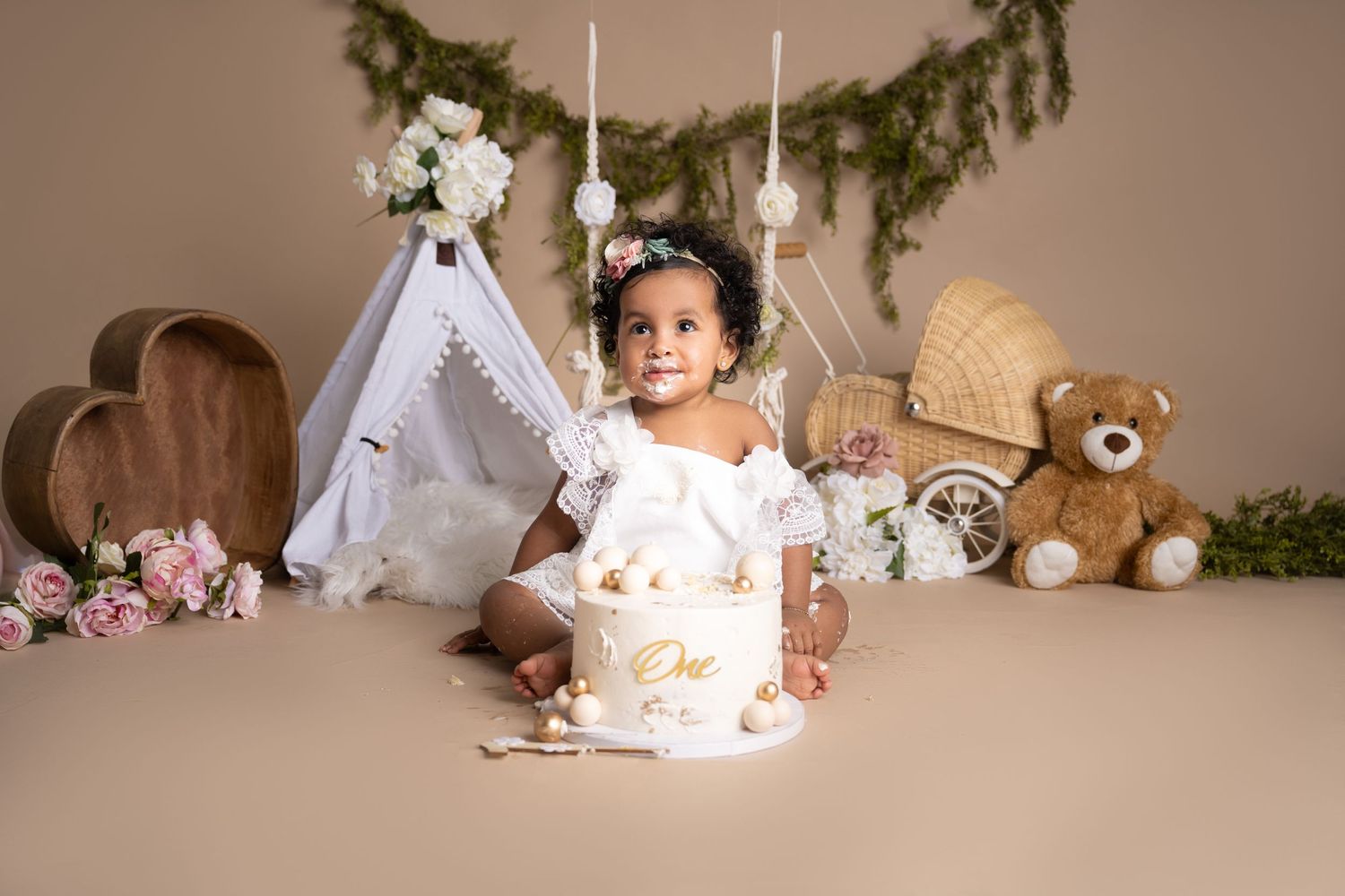 Enchanting boho-styled cake smash setup with teepee, flowers, and teddy bear.
