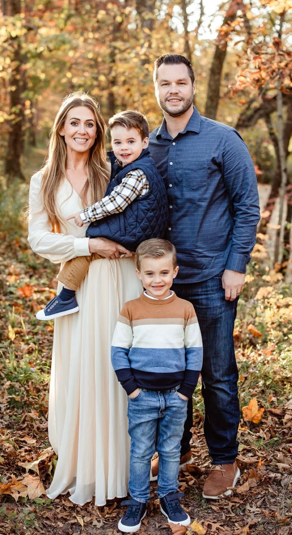 Outdoor fall photo session in woodland setting with autumn leaves on the ground.