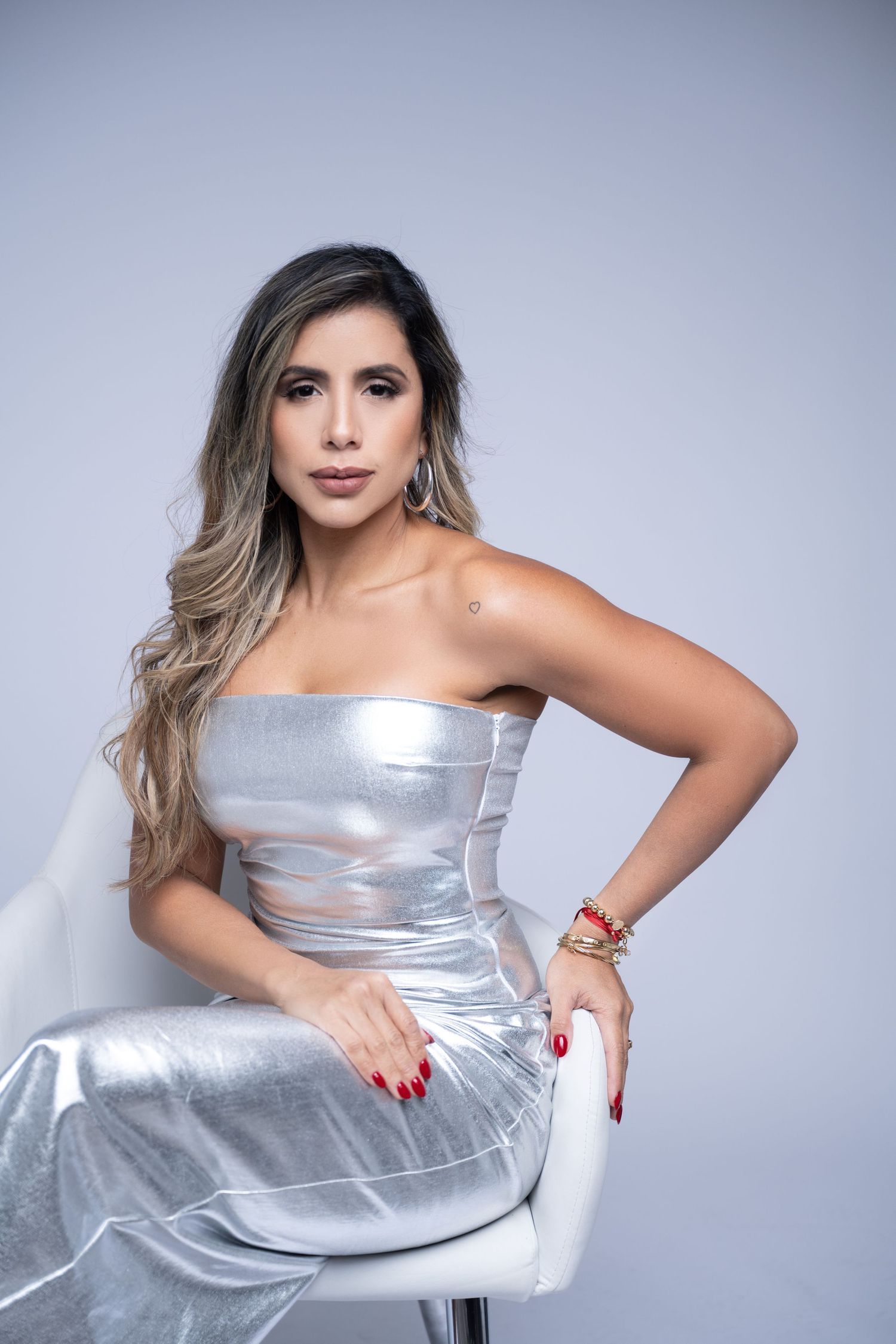 Elegant pose in metallic silver dress against light gray background.