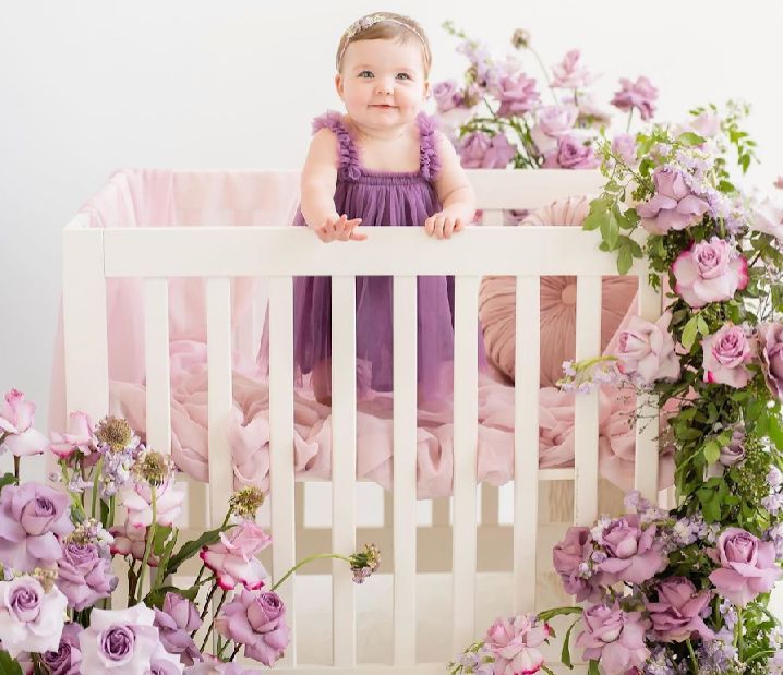 Floral backdrop with pink roses and white picket fence creates a romantic spring photography setting.