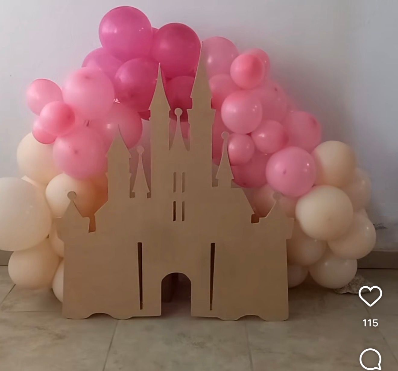 Wooden castle cutout backdrop decorated with pink and cream balloon arch for a princess-themed party.