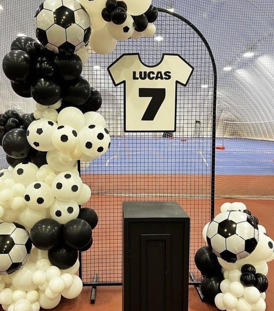 Soccer-themed birthday balloon arch with black and white balloons and jersey sign reading Lucas 7.