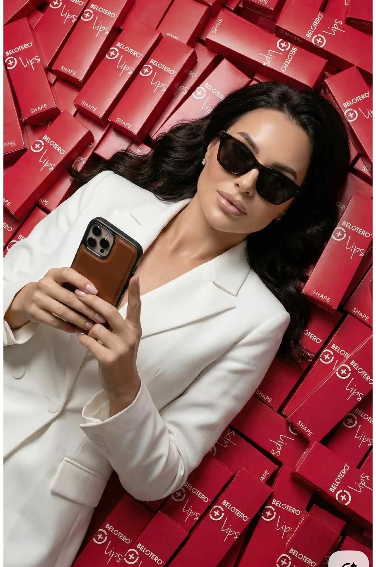 Woman in white blazer and sunglasses taking selfie surrounded by red Target boxes.