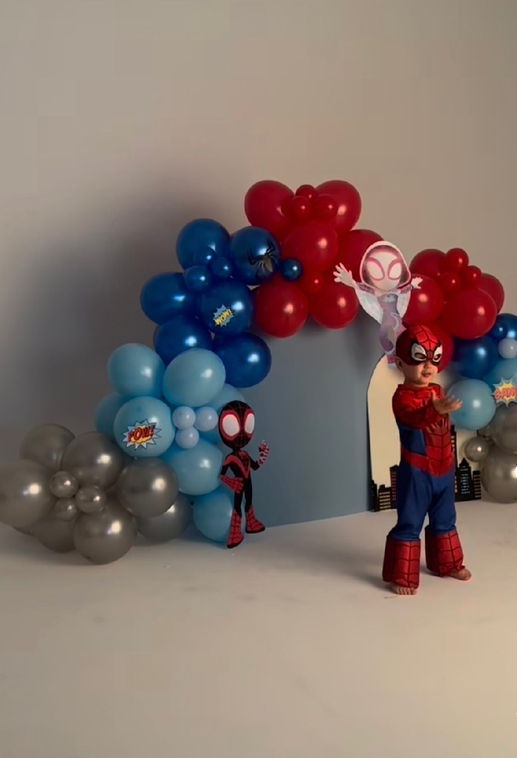 Spider-Man themed party decor featuring red, blue, and silver balloon garland with superhero figurines.