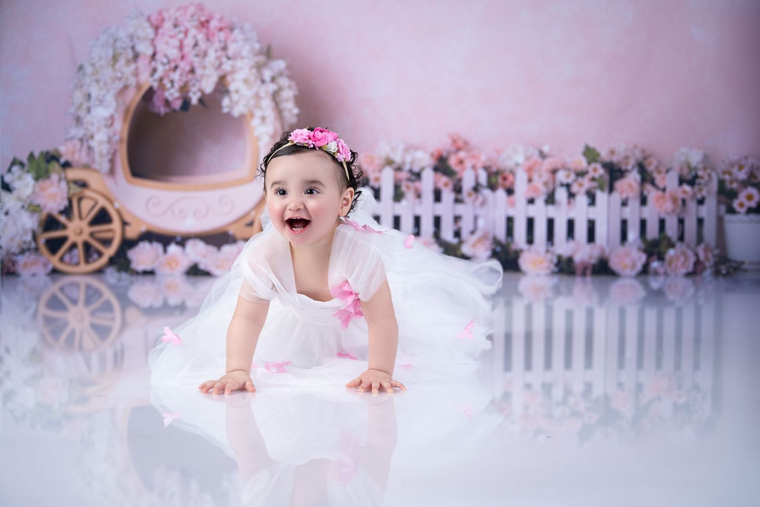 Dreamy pink garden scene with white picket fence and floral carriage backdrop.