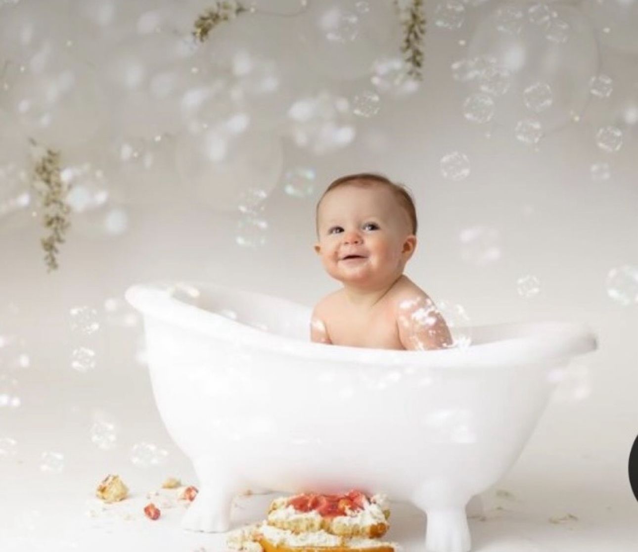 Baby photography with white paper boat props and floating bubbles against light backdrop.