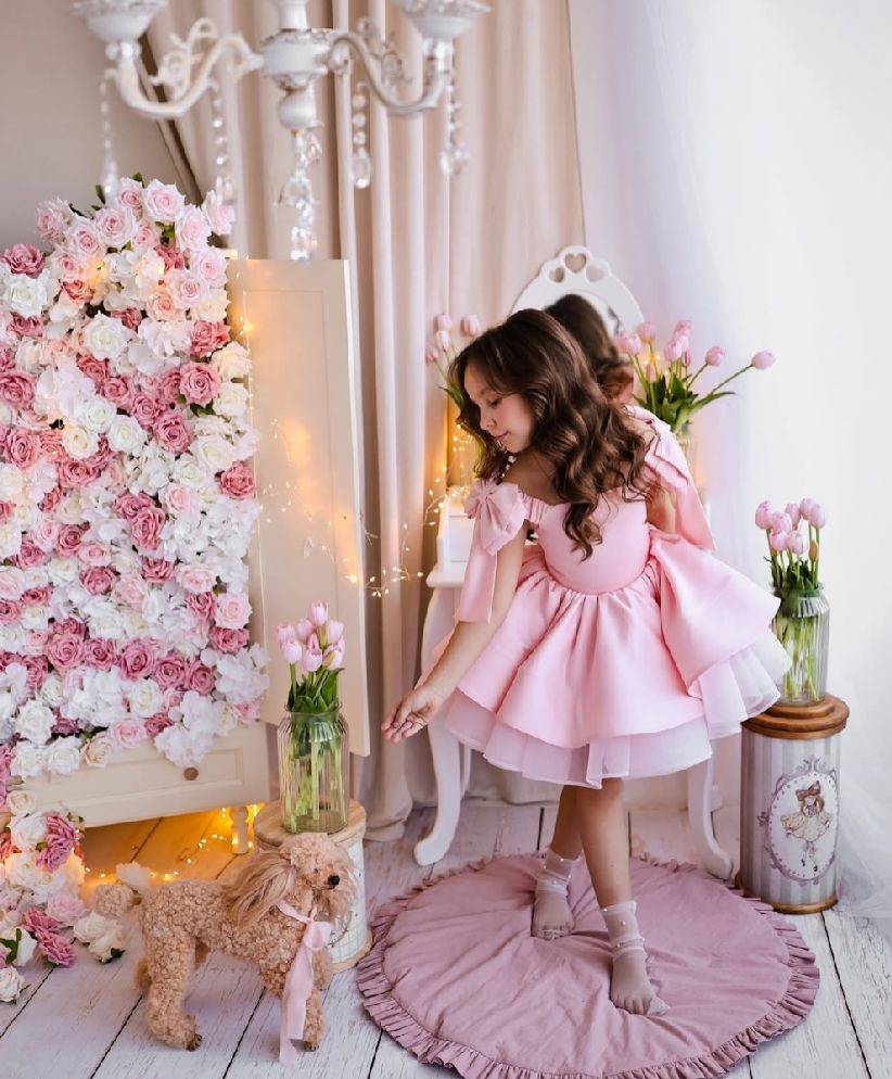 Pink floral birthday photoshoot setup with romantic decor and soft lighting against white backdrop.