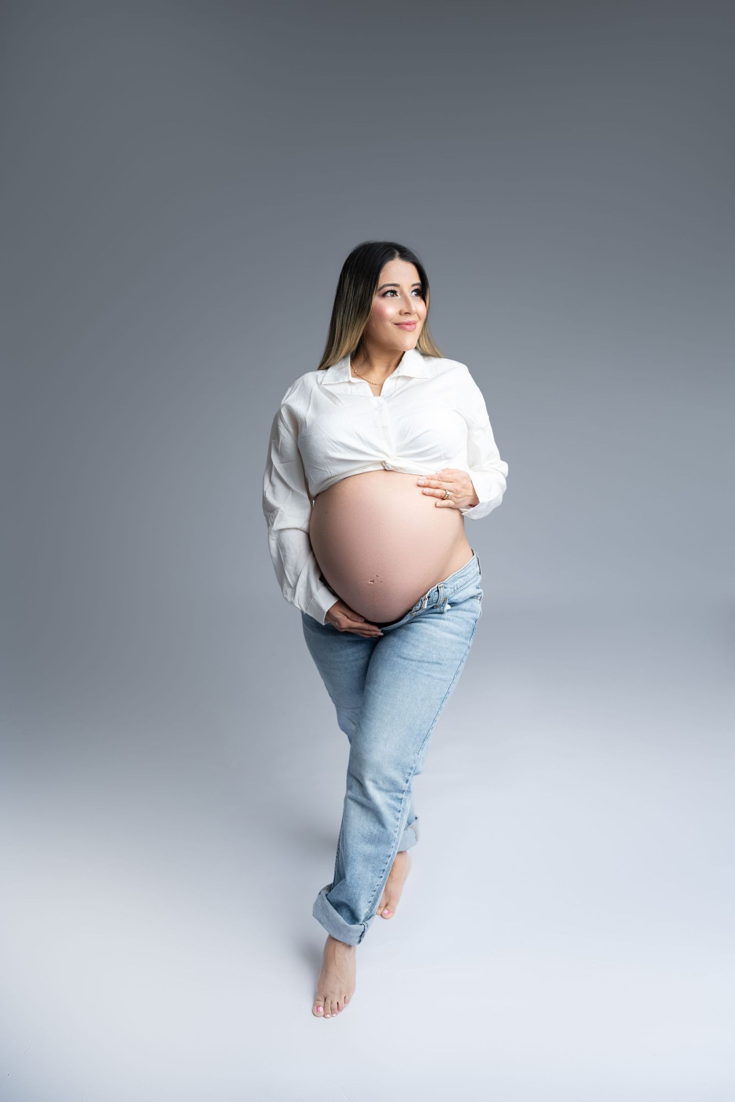 Minimalist maternity photo with white button-down shirt and light denim.