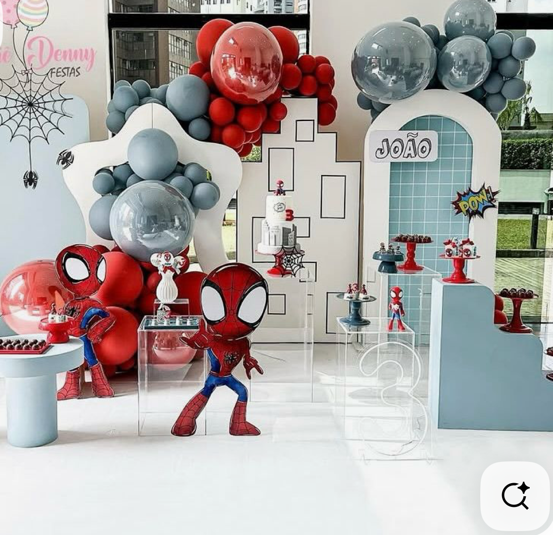 Spiderman themed birthday party setup with red and gray balloon garland, character figurines, and decorated display stands.