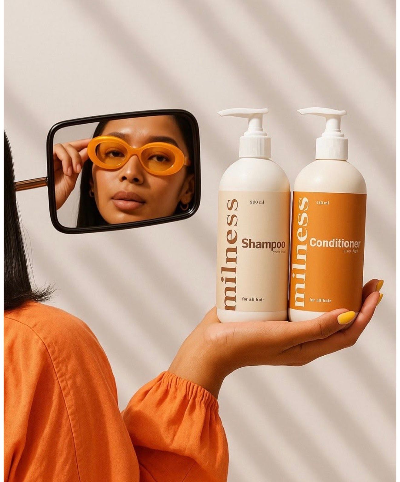 Woman in orange outfit holding Milness Shampoo and Conditioner bottles, wearing orange sunglasses reflected in a mirror.