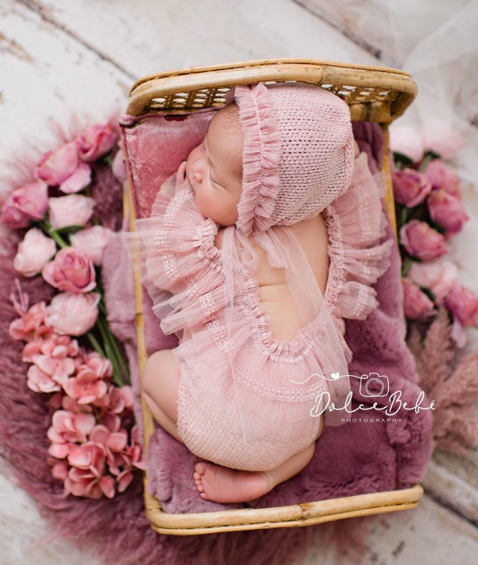 Pink baby booties and floral decorations arranged in a delicate vintage composition with soft lighting.
