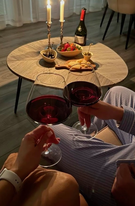 A candlelit table with wine glasses and red wine creates an intimate dining atmosphere.