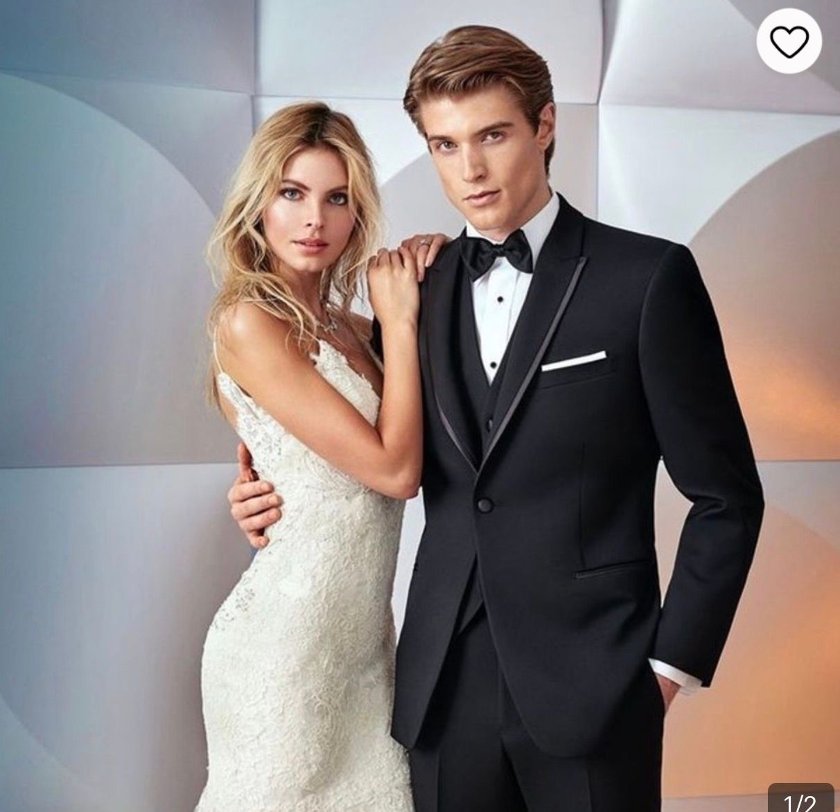 Elegant couple in formal wedding attire, woman in white lace gown and man in classic black tuxedo with bow tie.