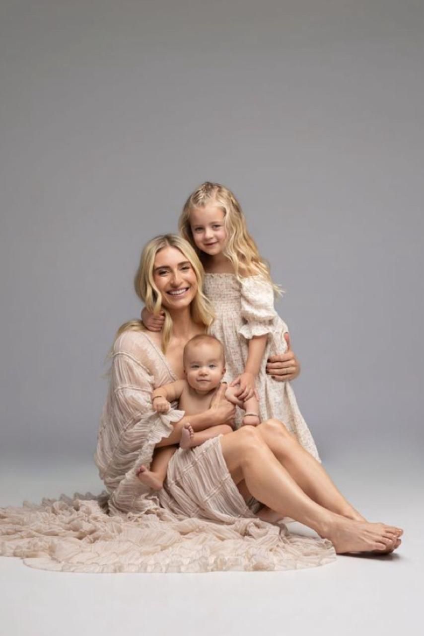 A soft and dreamy family portrait session in blush tones against a light gray backdrop.