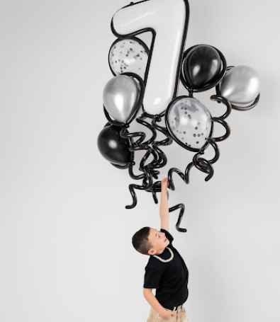 A series of black and white photos showing a figure playfully interacting with floating black and white balloons.