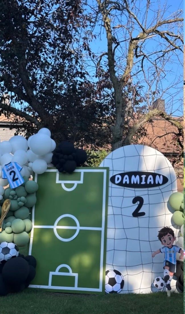 Soccer-themed 2nd birthday party backdrop for Damian with balloon garland, football field board, and goal net decoration.