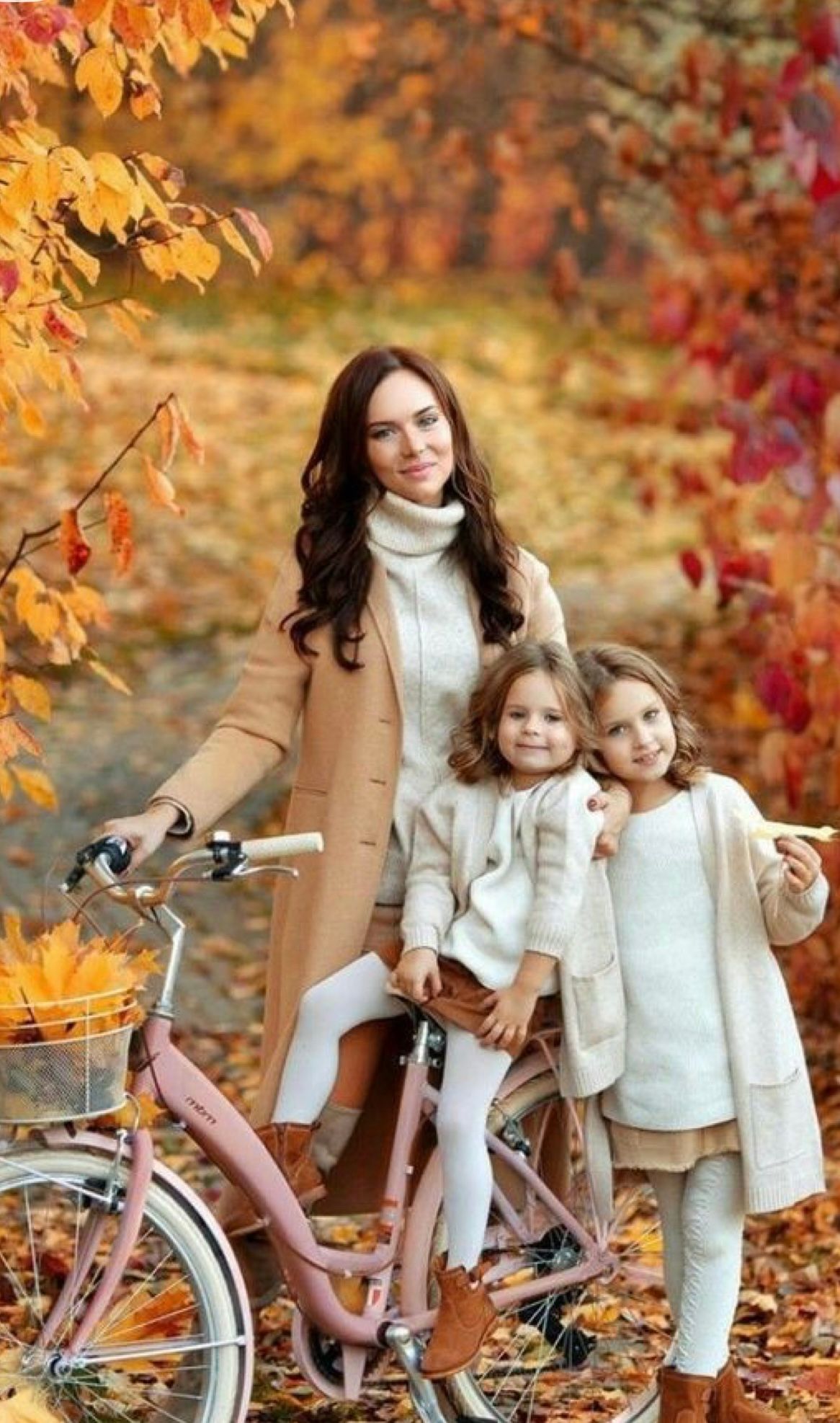 Autumn photo session with vintage pink bicycle and cozy sweaters against golden fall foliage background.