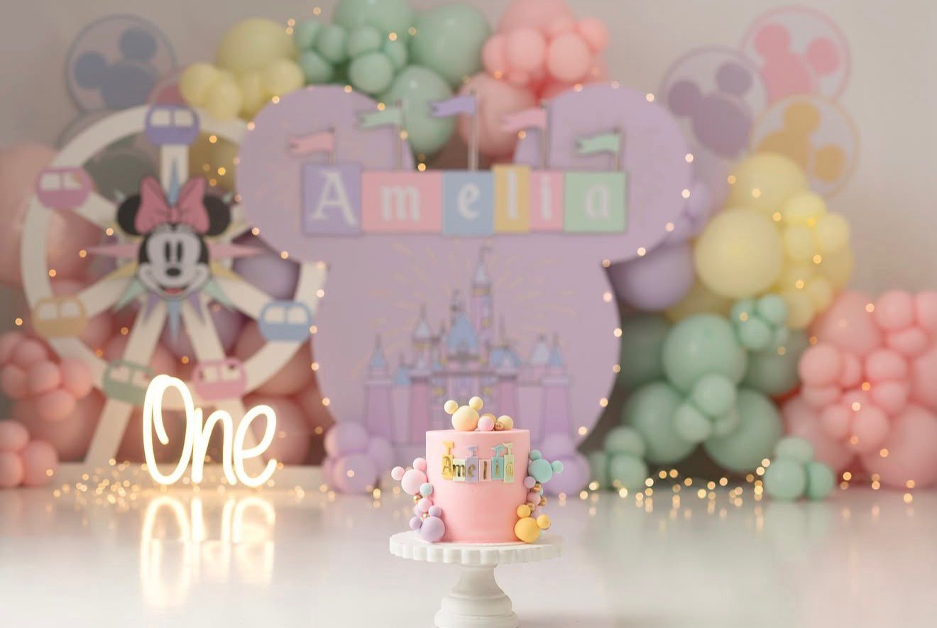 Amelia's first birthday cake smash with Minnie Mouse theme, pastel balloons, castle backdrop, and glowing One sign.