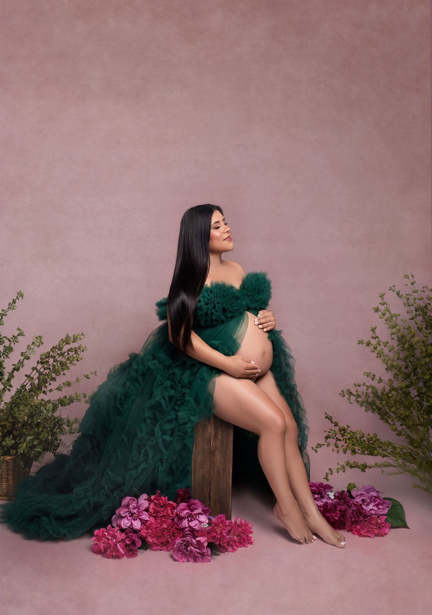 Artistic portrait series showing a figure in emerald tulle dress reclining against pink wall with purple hydrangeas.