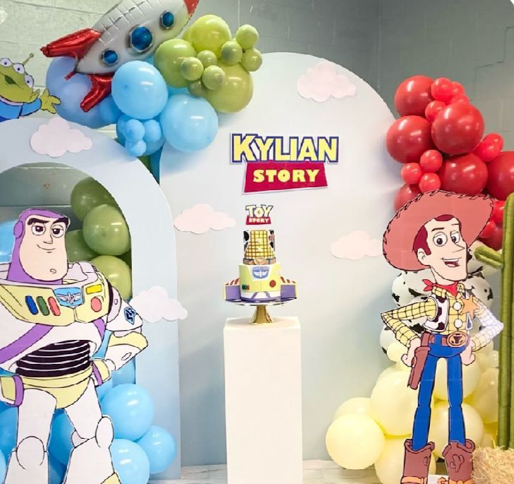 Toy Story themed party backdrop with colorful balloon garlands and character standees.