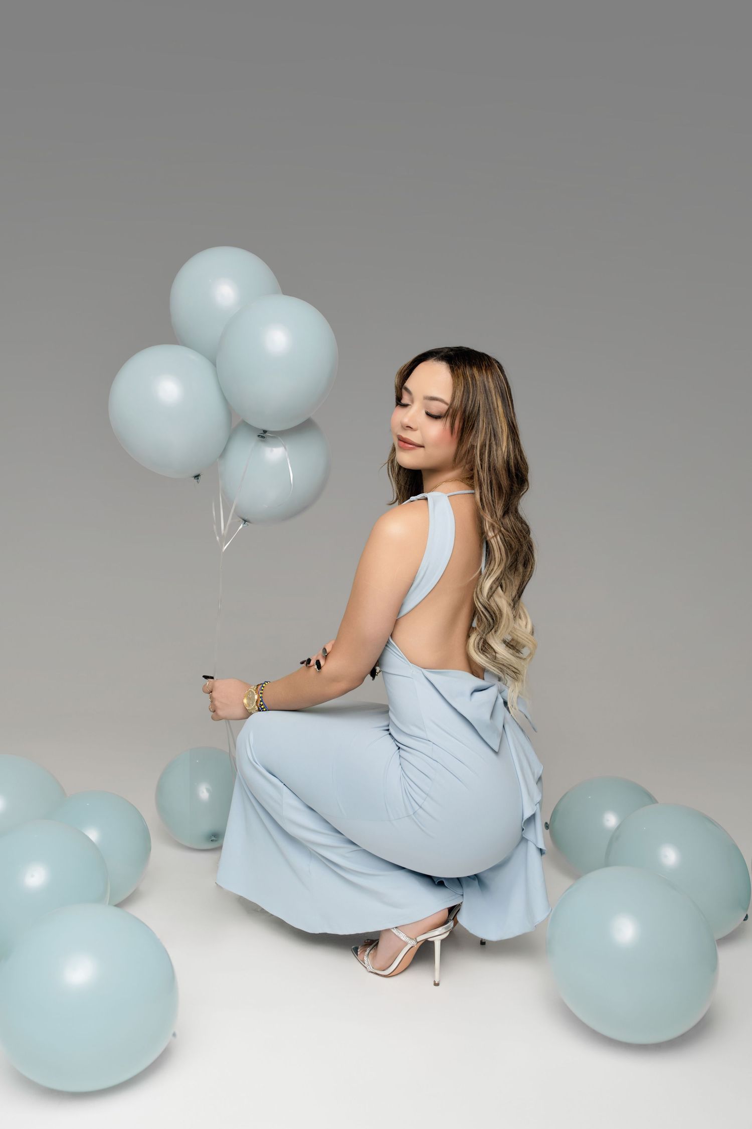 A series of studio portraits featuring a person in a light blue dress posing with matching pastel blue balloons.