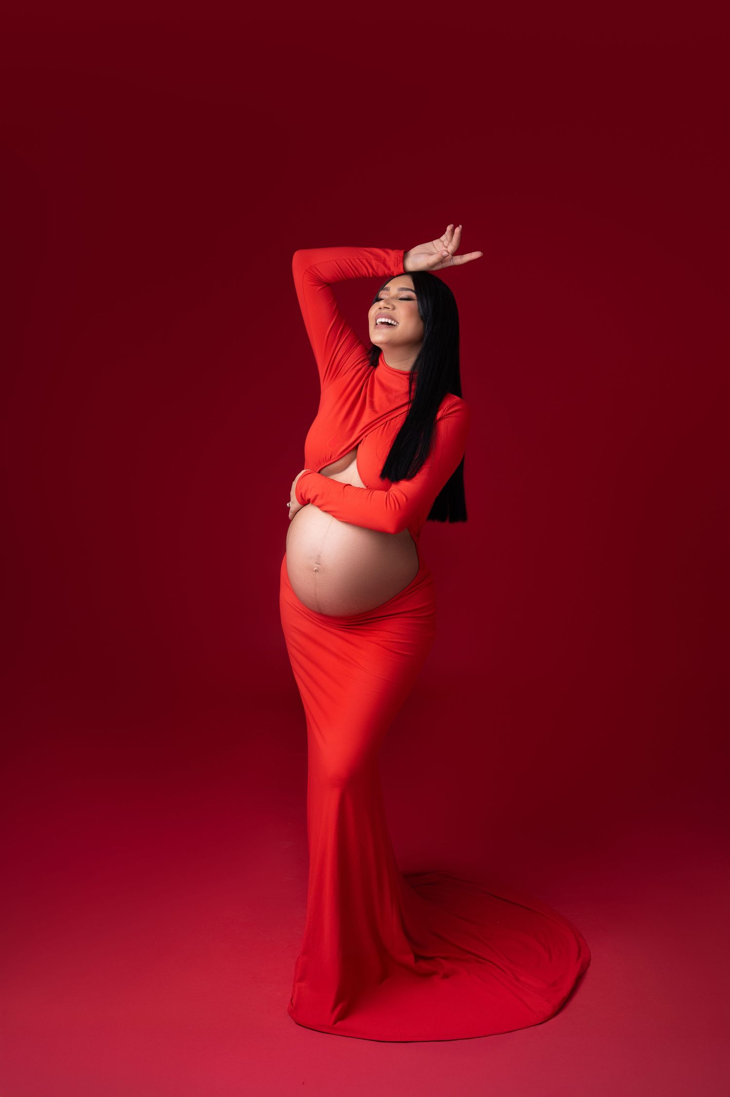 Artistic maternity photo series showing figure in flowing red dress against burgundy backdrop striking elegant poses.