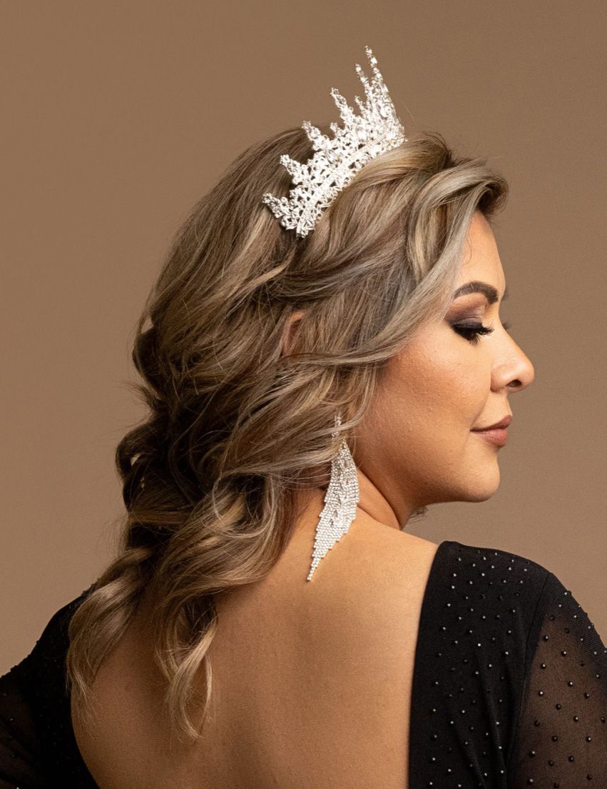 Side profile view of a person wearing a black dress and delicate white lace hair accessories against a neutral background.