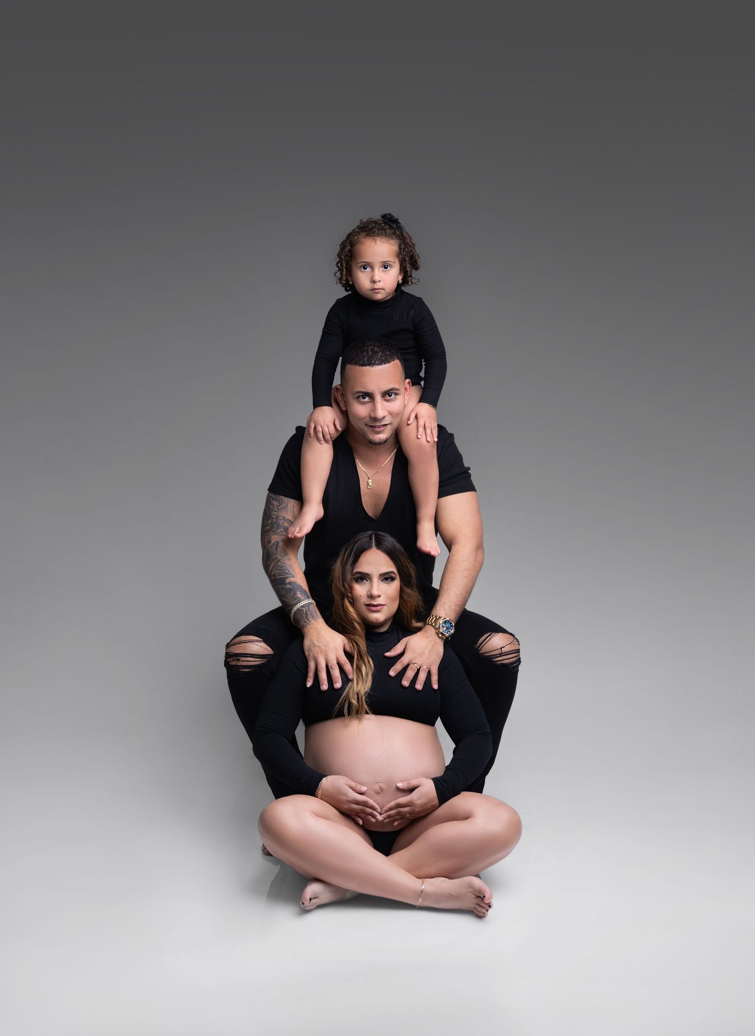 A series of black and white maternity photos showing a couple in intimate poses against a light background.