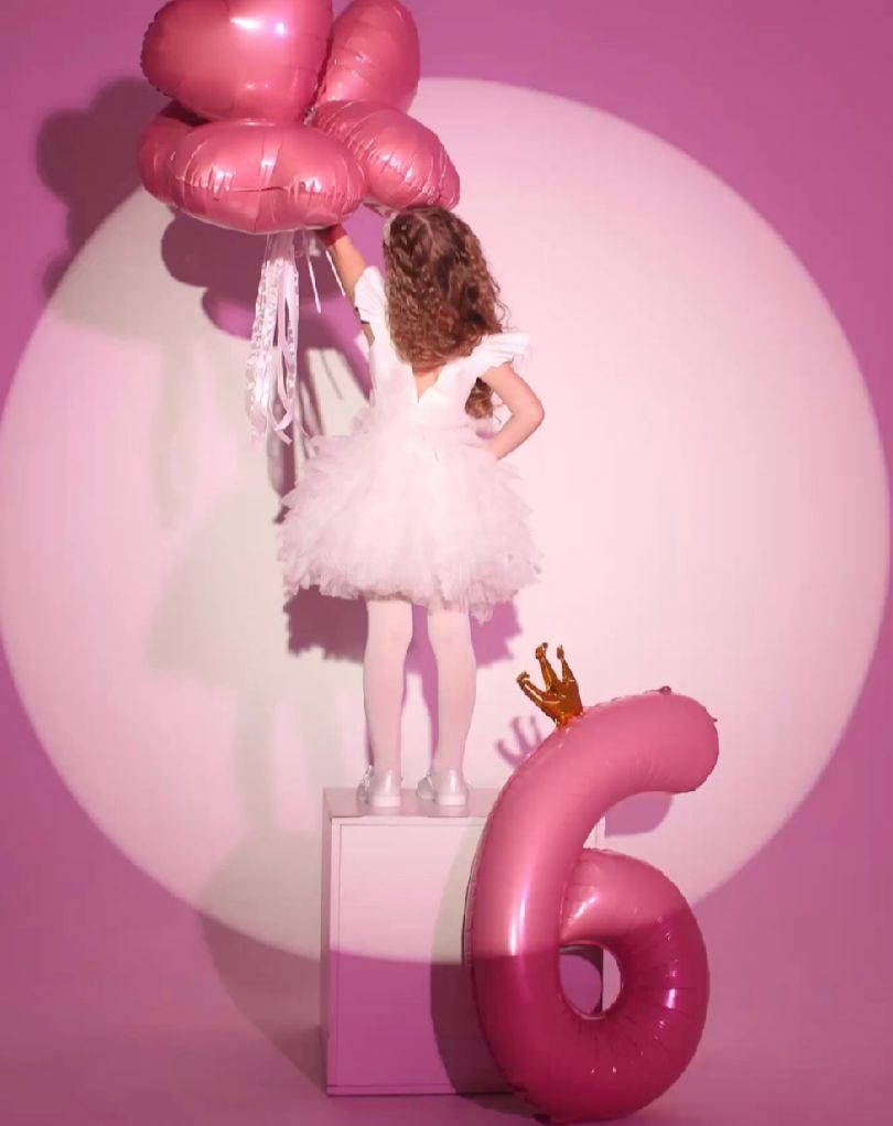 Pink and white balloon art installation against a soft pink background creates a dreamy atmosphere.