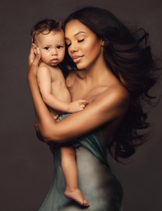 Intimate mother and child portrait series with dramatic lighting against dark background.