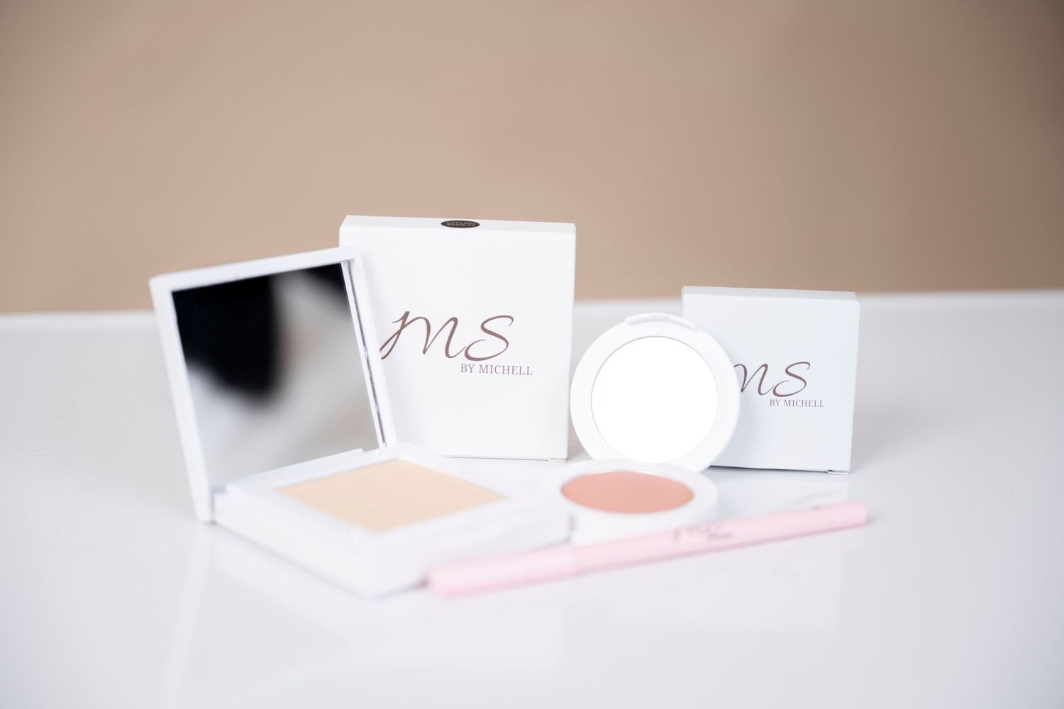Beauty product packaging with MS branding and pink cosmetic items on white surface.