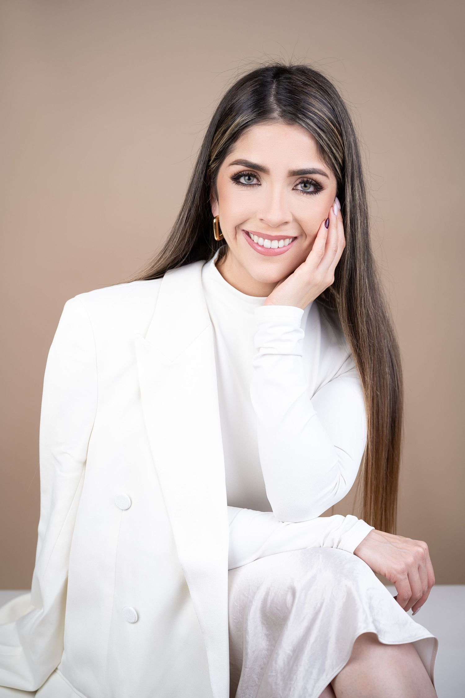 Professional portrait of someone in an elegant white blazer against a neutral backdrop.