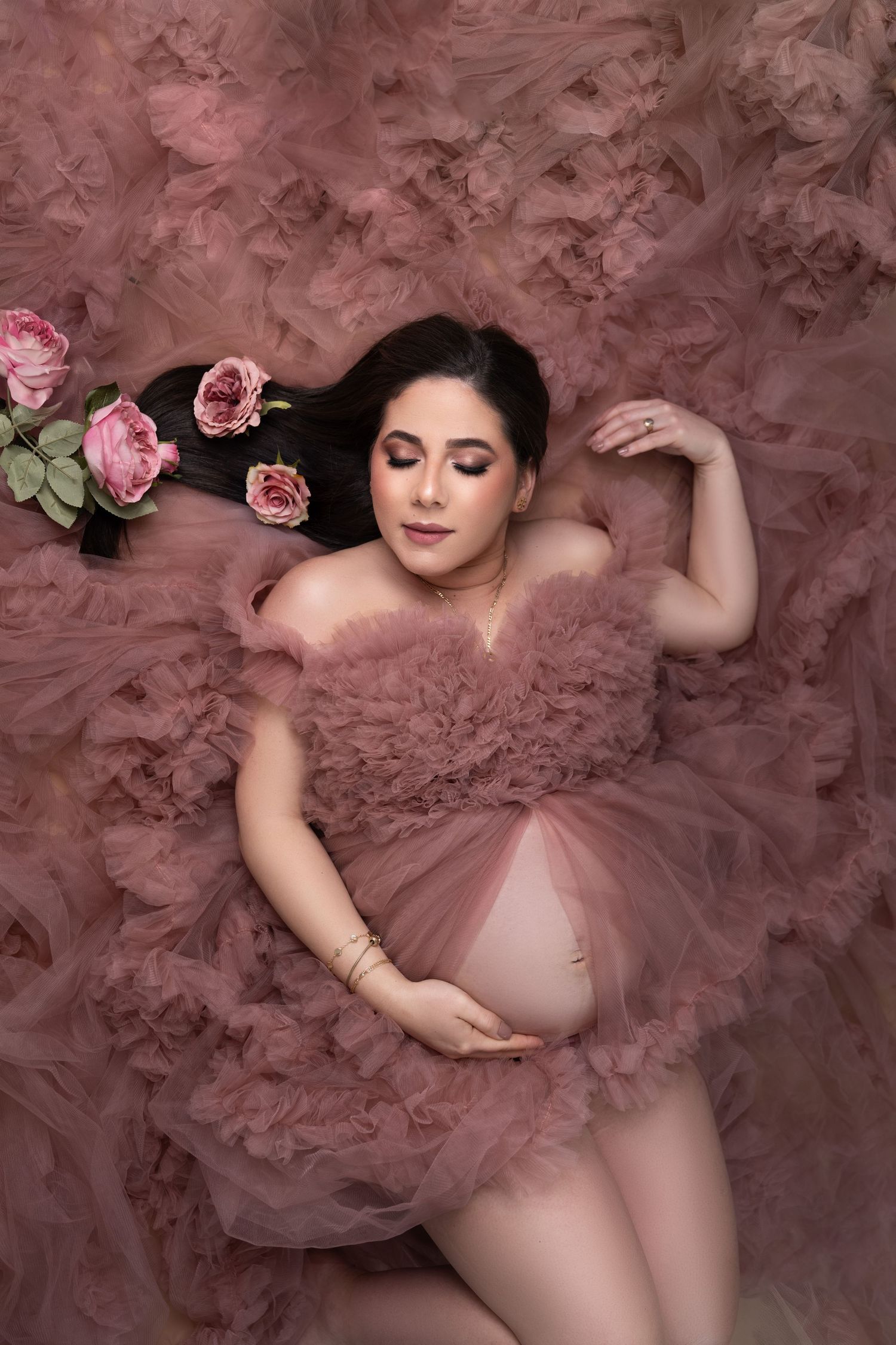 Artistic boudoir photography with pink roses and flowing tulle fabric creates a romantic and ethereal aesthetic.
