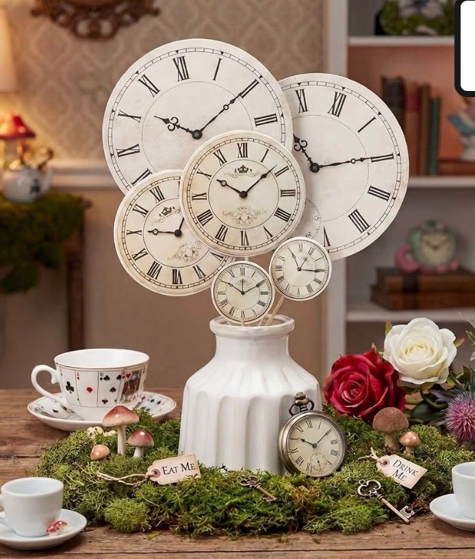 Alice in Wonderland tea party centerpiece with vintage clocks in a white vase, moss, red and white roses, and a playing card teacup.