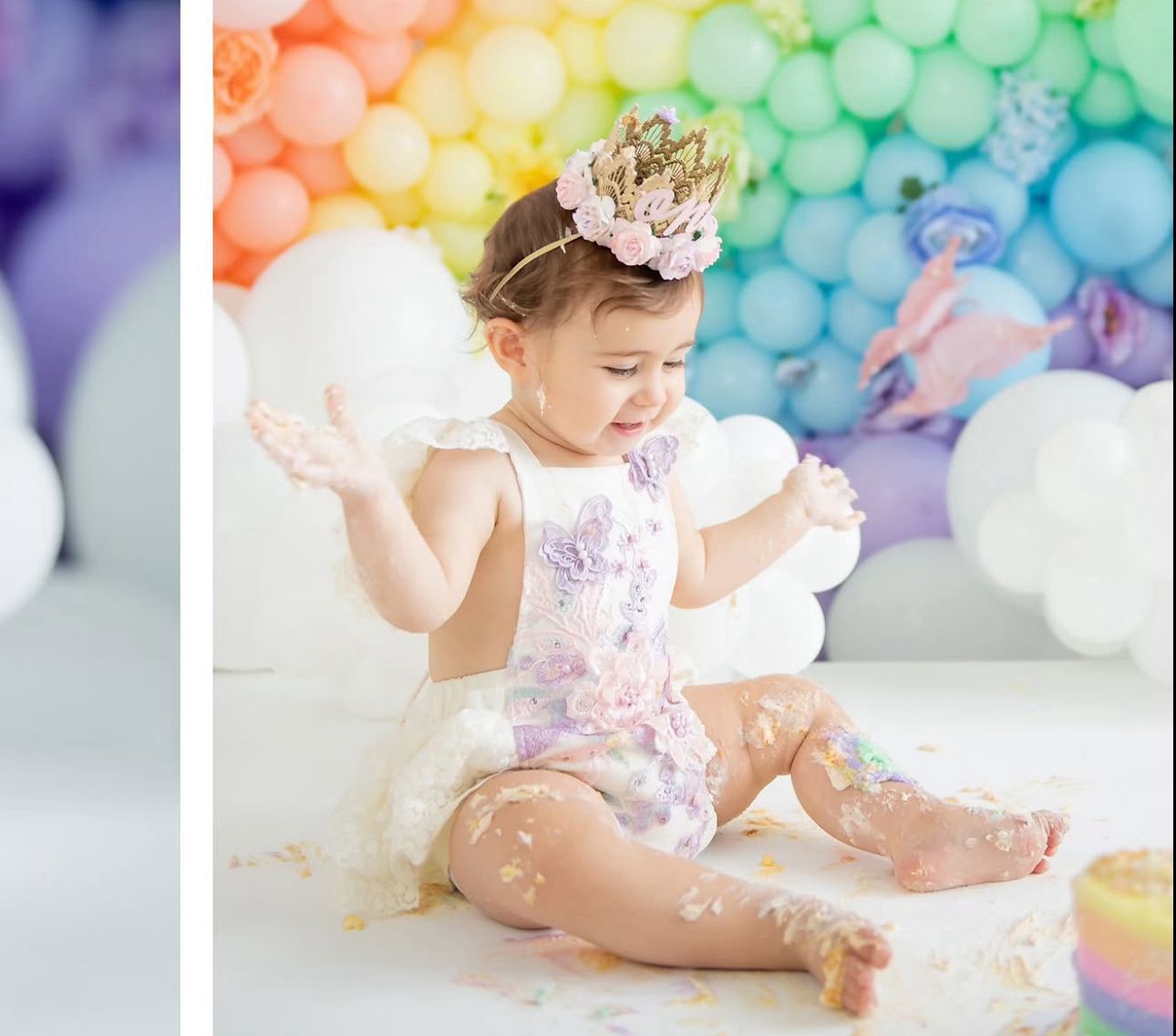 Pastel balloon backdrop with white cake smash setup featuring delicate decorations and soft lighting.