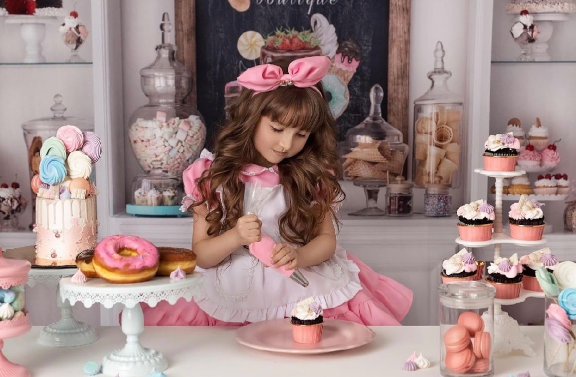 A pink and white dessert table decorated with cupcakes, macarons, and floral accents for a special occasion.
