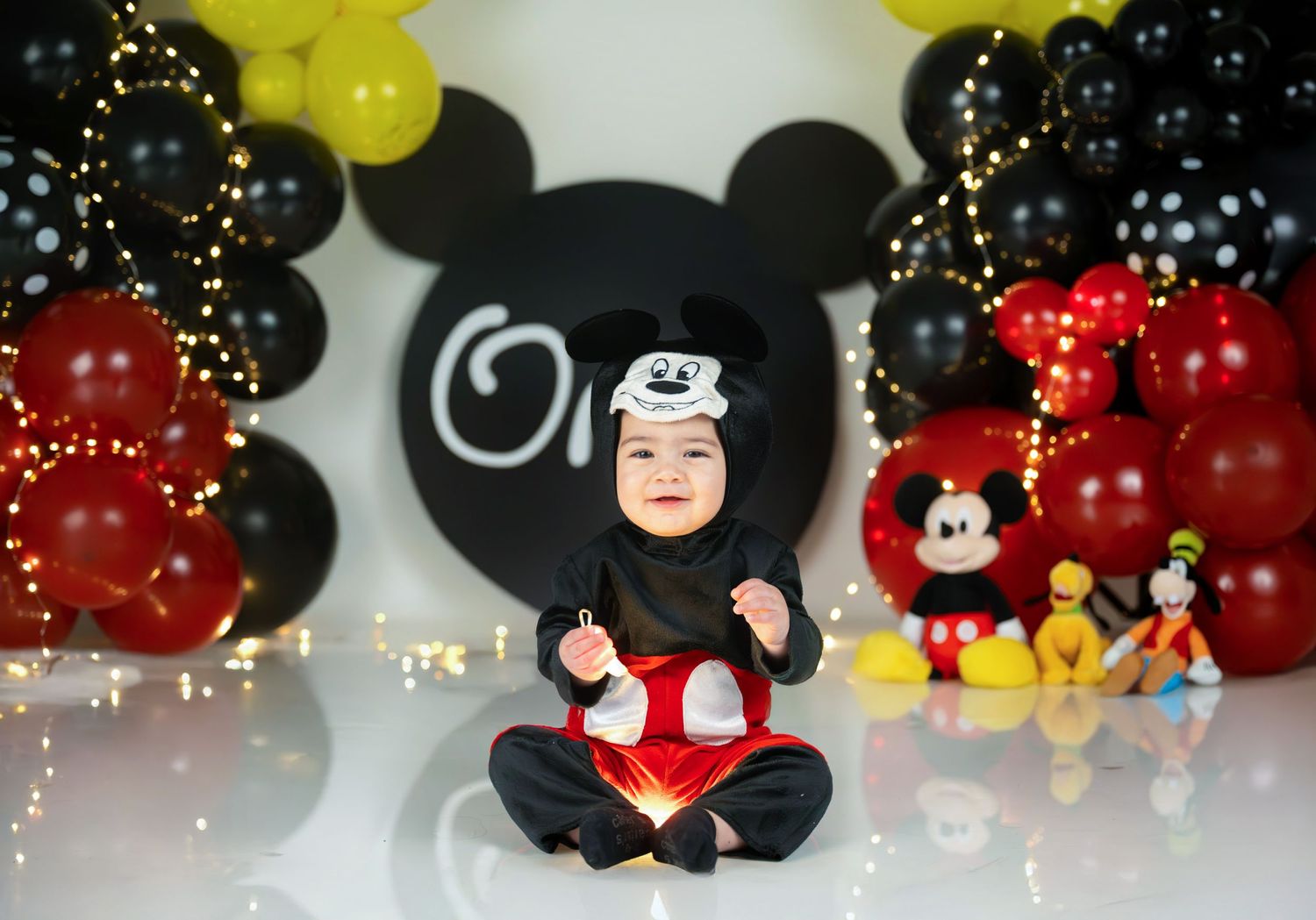 Mickey Mouse themed birthday setup with black and yellow balloon arch.