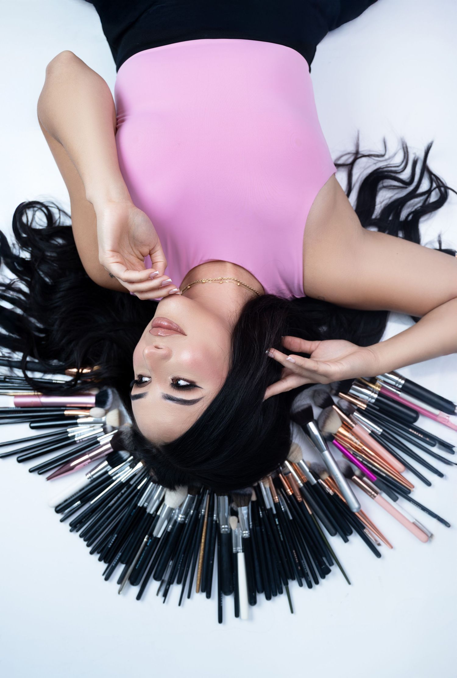 Overhead beauty shot featuring pink outfit and radiating makeup brush arrangement.