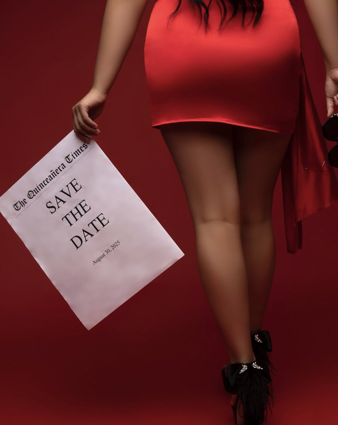 Woman in red dress holding a Save the Date newspaper announcement, walking away on a red background.