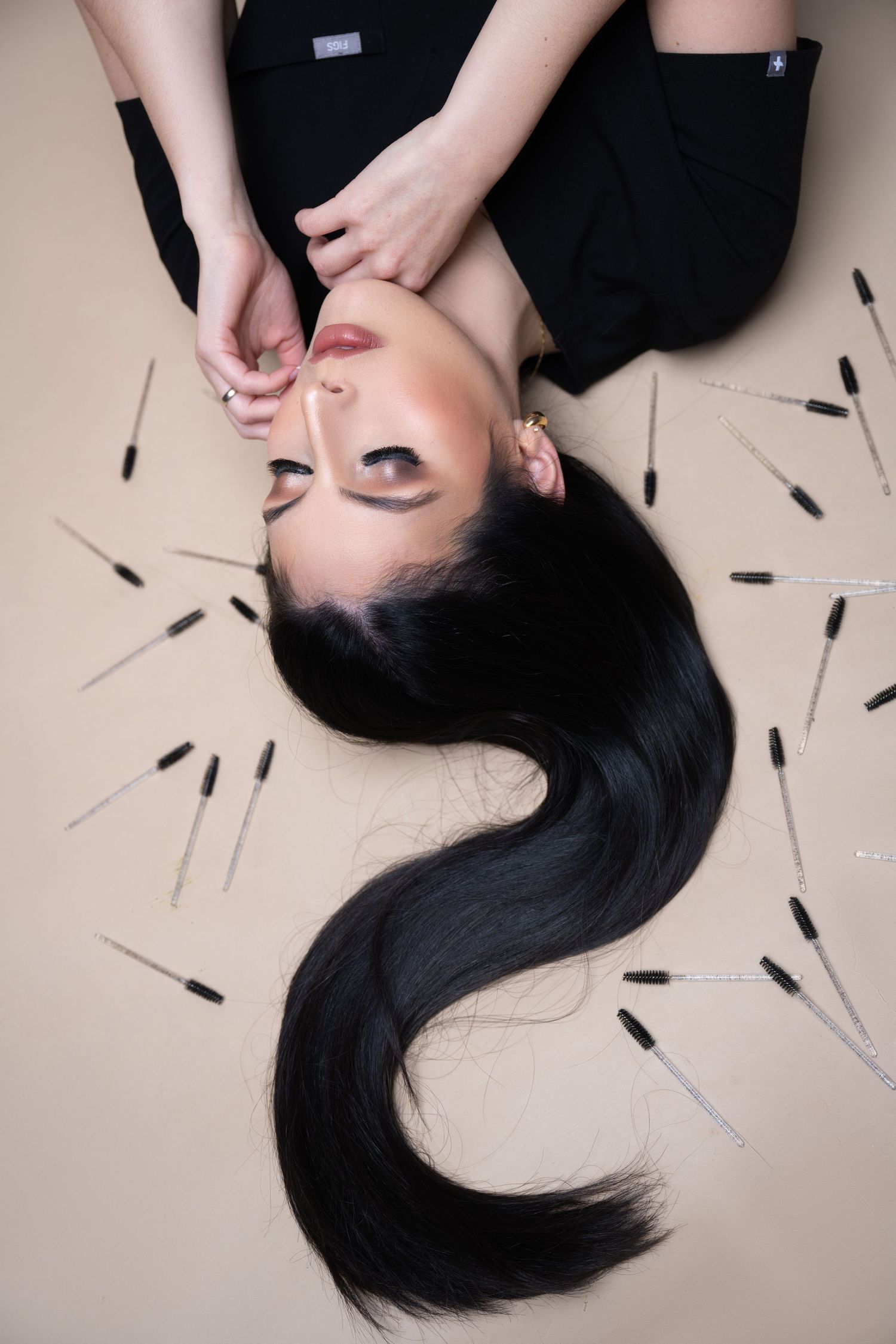 Artistic overhead portrait with long dark hair fanned out on beige background.