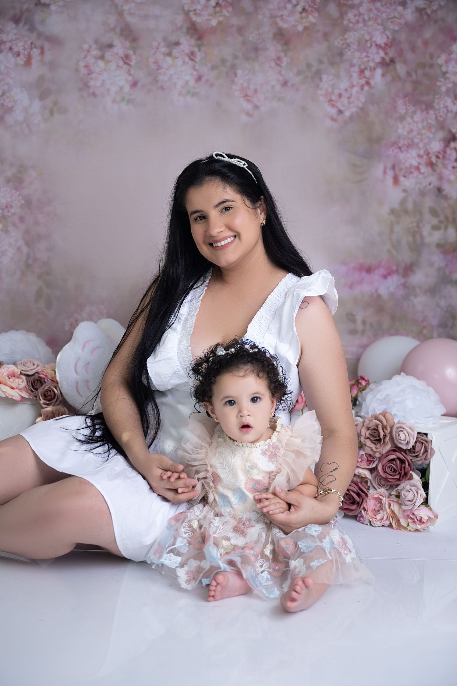 Pink floral backdrop with roses and soft lighting creates romantic photography setting.