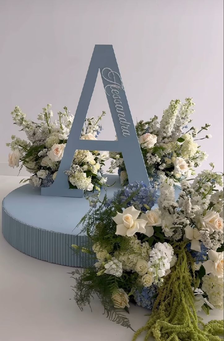 A large decorative letter A adorned with elegant white and blue floral arrangements on a light blue base.