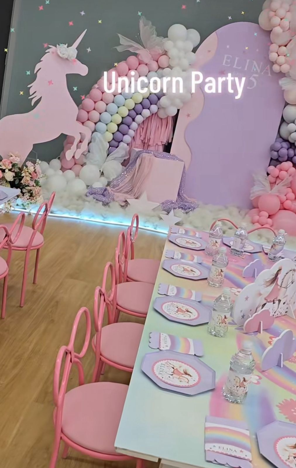 Magical unicorn-themed party setup with pink and purple balloon decorations, pastel table settings and whimsical decor.