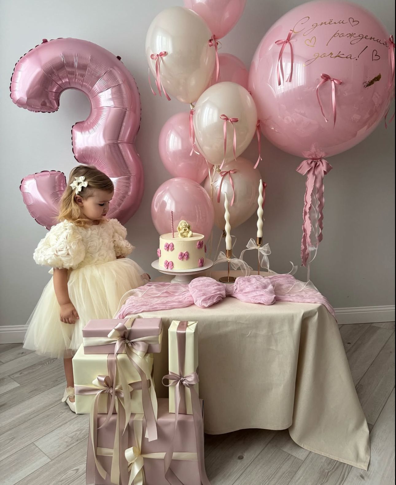 Pink and white balloon decorations create an elegant party setup with a table setting and yellow dress accent.
