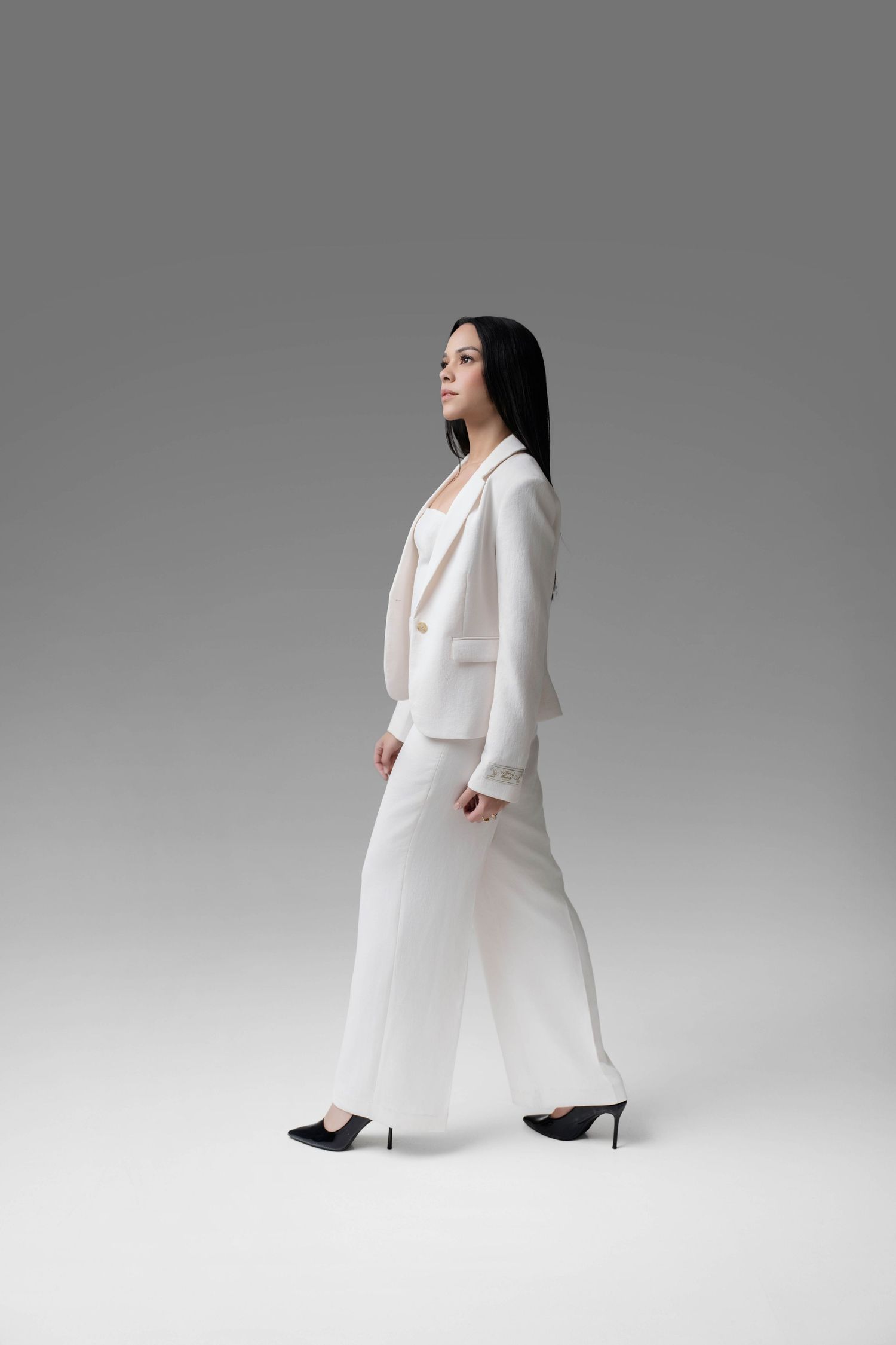 A figure in an elegant white pantsuit strikes dynamic poses against a light gray studio backdrop.