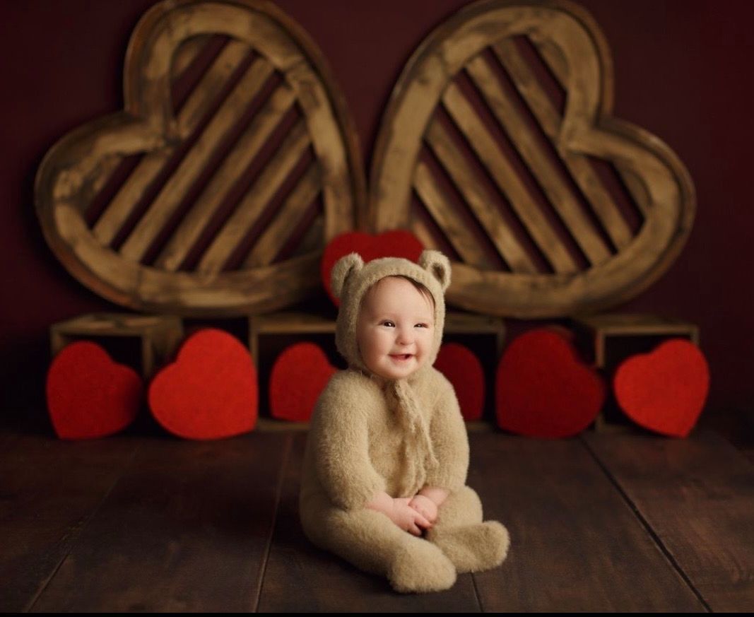 Cozy Valentine's day themed photo setup with wooden heart props and red decorative hearts against a dark background.