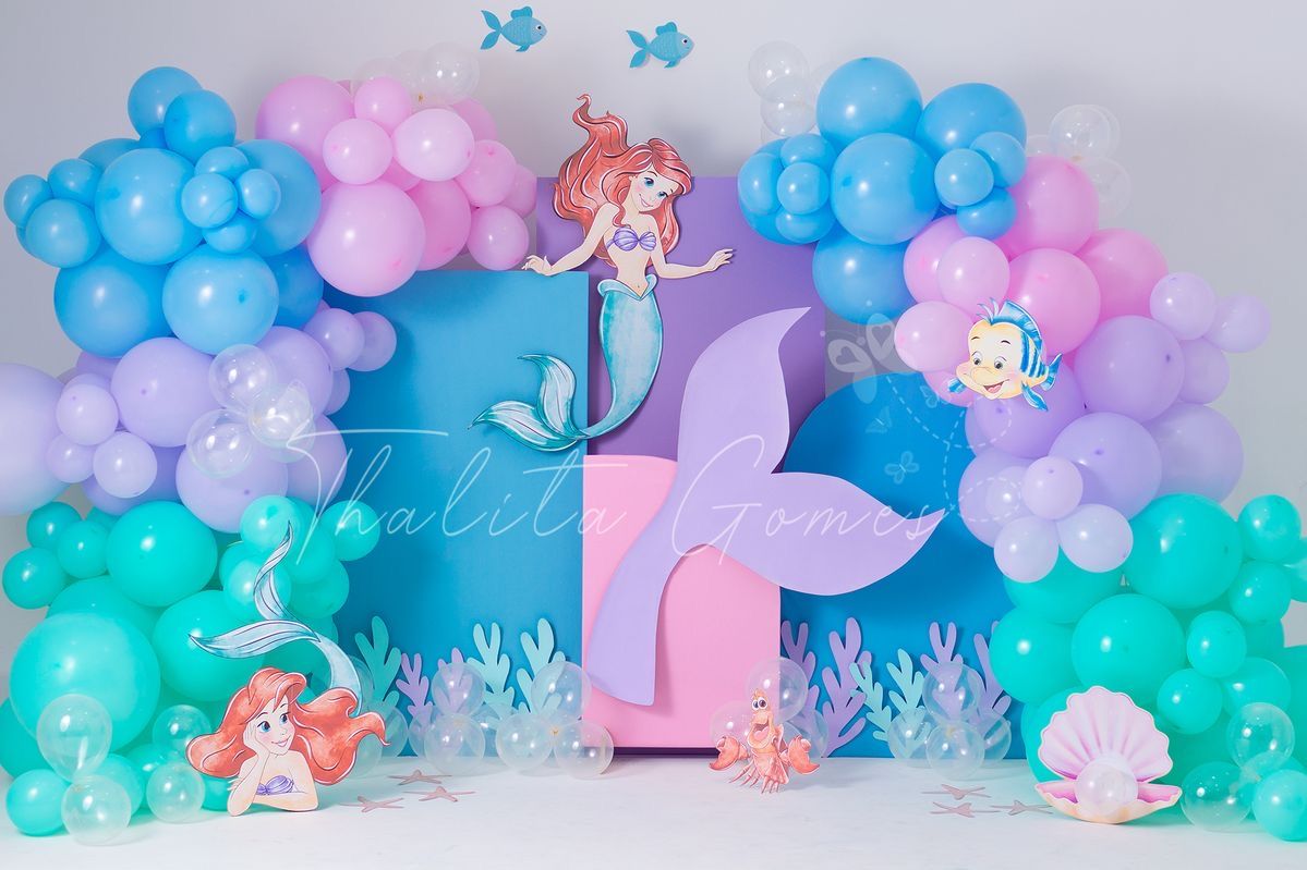 Little Mermaid themed birthday backdrop with colorful balloon garland, Ariel decorations, and teal mermaid tail centerpiece.