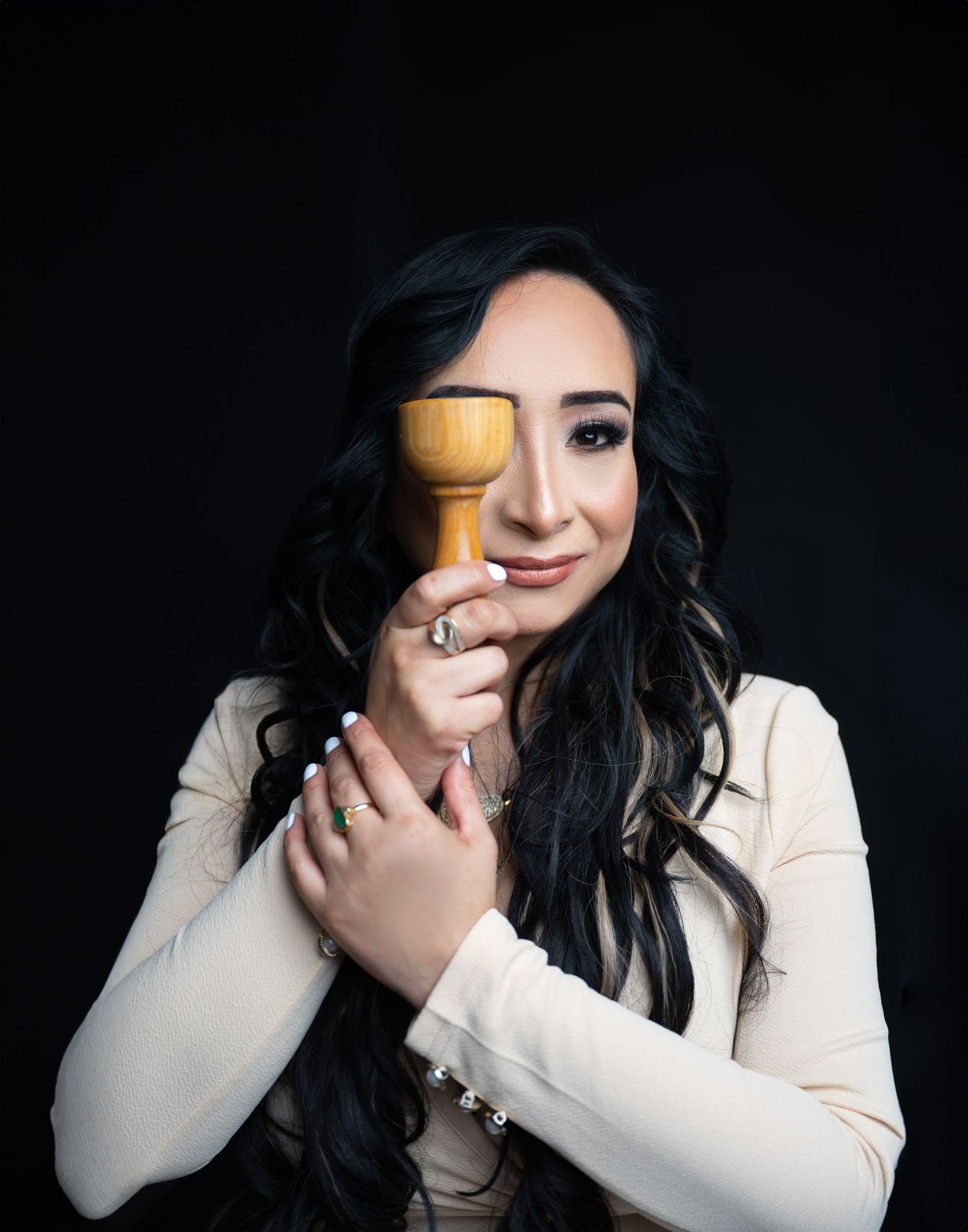 Studio portrait with wooden beauty tool against dark background.