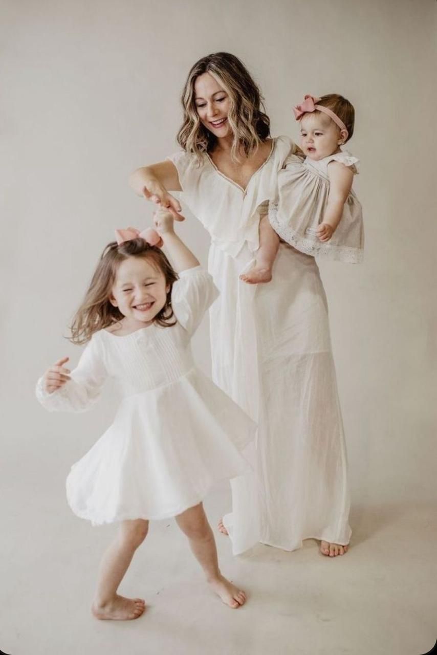 A mother and daughter dance together in flowing white dresses against a neutral backdrop in a series of candid shots.