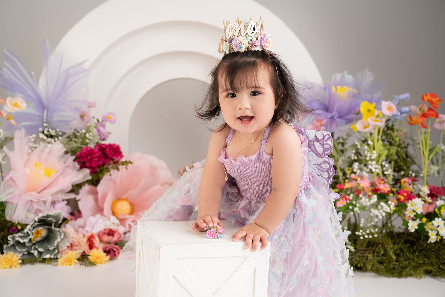 Festive floral photoshoot setup with decorative arch and colorful flowers in the background.
